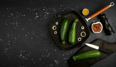 Koyu bir masada tavada taze yeşil kabak. Yukarıdan manzara. Boşluğu kopyala.