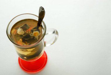 Beyaz arka planda otlarla çay. Beyaz bir yüzeyüzerinde nane ve papatya ile bitkisel çay. Tedavi ve sağlık kavramı.