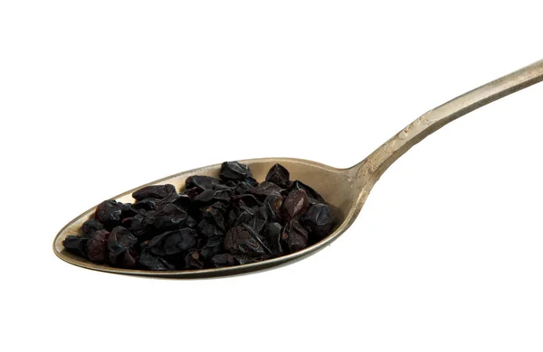 Dried barberry in an old spoon isolated on a white background. Seasoning on isolate. View from above.