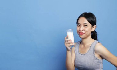 Güzellik genç mix-race asyalı kadınlar büyük parlak mavi renkli arka planda içmeye hazır bir süt bardağı tutan