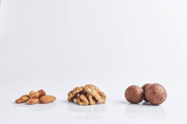 Beyaz arka planda badem, ceviz, macadamia. Bir kaç avuç çiğ fındık. metin için boşluk kopyala.