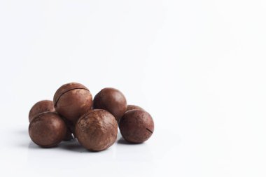 Beyaz arka planda karamel aromalı bir avuç macadamia fındığı. Çiğ fındık yakın plan. metin için boşluk kopyala.