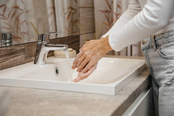 Human washes his hands with soap in the bathroom. Preventing the spread of viral infection, coronavirus (COVID). Clean hands are a guarantee of health