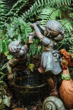 Tayland - 2019. Phuket Botanik Bahçesi. Çocuk heykeli. Musluktan akan suyla oynuyorlar..