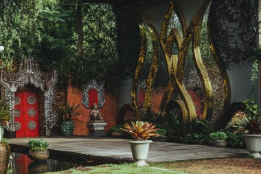 Tayland - 2019. Phuket Botanik Bahçesi. Botanik bahçesinin merkezi girişi. Gümüş süslemeler ve altın dev su zambaklarıyla çerçevelenmiş kırmızı kapılar..