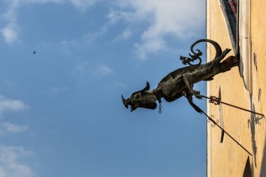 Eski bir evin duvarında ejderha şeklinde eski bir drenaj borusu yüksekliğinde yükselen bir kuş ile mavi bir gökyüzünün arka planına karşı.