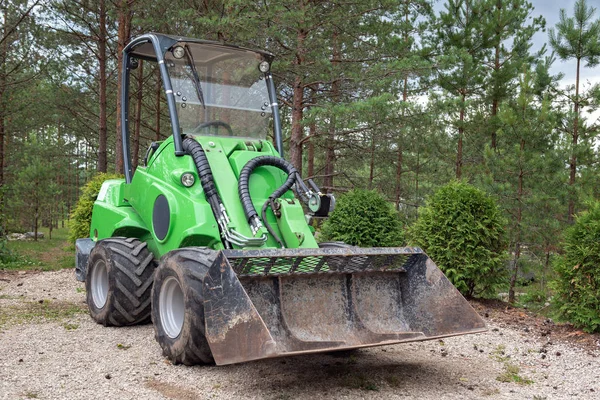 Ormanda küçük yeşil traktör veya Yükleyici-Kompakt yükleyici Park