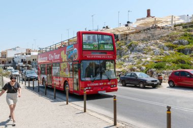 Rethymno, Girit - Ağustos 2018: Kırmızı gezi otobüsü cadde boyunca sürüş.