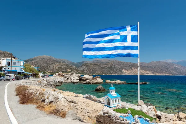 Büyük mavi Yunan bayrağı ve küçük kilise Palaiochora coast kasaba adada Crete, Yunanistan