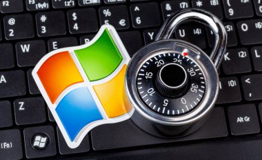 Microsoft Windows logosu ve şifreli bir asma kilit, dizüstü bilgisayarın klavyesinde duran şifre kilidi sembolü. Sistem güvenliği ve veri güvenliği, hackleme, soyut kavramlardan yararlanma