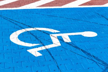 Engelliler için boş park yeri, yerdeki mavi tekerlekli sandalye sembolü. Otopark alanındaki kaldırımda engelli göstergesi için park yeri, yakın çekim. Erişilebilirlik kavramı