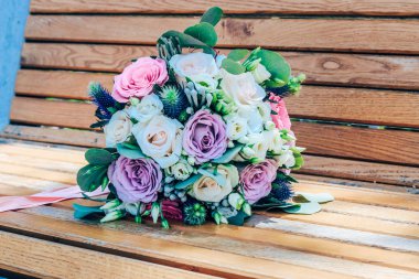 Ahşap arka planda mor ve bej güller ve kar beyaz Lisianthus modern düğün buket. Close