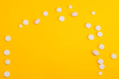 Farklı haplar ve vitaminler sarı bir arka plan üzerinde dağınık. metin için alan, yakın çekim