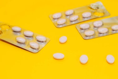 Farklı hap ve vitaminlerin yakın çekim sarı bir arka plan üzerinde dağınık, bir paket hap