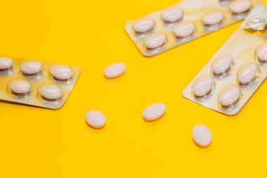 Farklı hap ve vitaminlerin yakın çekim sarı bir arka plan üzerinde dağınık, bir paket hap