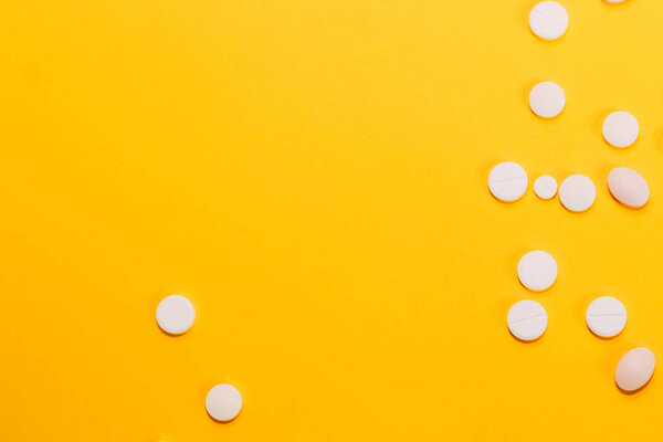 Different pills and vitamins are scattered on a yellow background. space for text, closeup