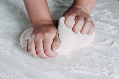 Beyaz ahşap masa arka plan üzerinde kadın eller ile hamur yapma. Beyaz masada ekmek hamuru hazırlayan kadın fırıncı.