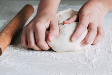 Beyaz ahşap masa arka plan üzerinde kadın eller ile hamur yapma. Beyaz masada ekmek hamuru hazırlayan kadın fırıncı.