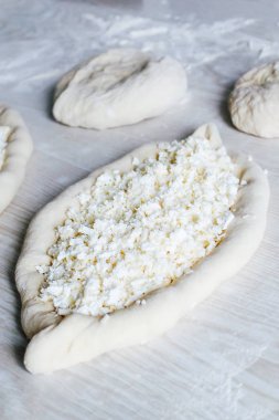 Suluguni Peynirli Ev Yapımı Ajarian Khachapuri. Çalışma aşaması. Pişirme için hazırlık. Pişirmeden önce Çiğ Suluguni
