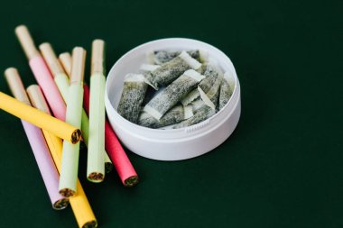 Çok renkli sigaralı yuvarlak bir kutu snus. Sigara, nikotin kesesi..