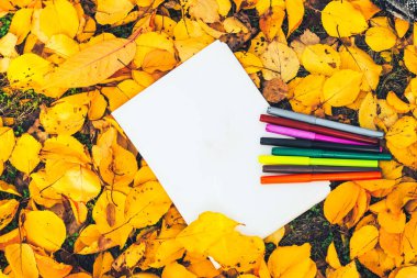 Sarı sonbahar yapraklarının arka planında yazı için boşluk olan boş bir sayfa. Planların ve hedeflerin listesi.
