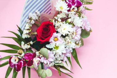 İçinde bir buket çiçek olan bir zarf şeklinde kutu. Orkideler, yeşillikler, kasımpatılar ve güller.