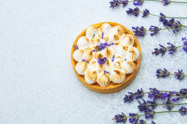 Çok güzel işlenmiş bir turta, lavanta filizi ile süslenmiş krema zirvelerine sahiptir..
