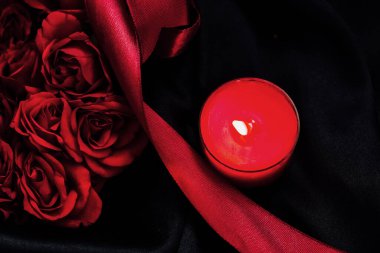 Kandilden gelen yumuşak kırmızı ışık, canlı kırmızı güllerin ve akan kurdelenin yanında sıcak bir ışık saçar. Bu sahne romantik bir ortam sunuyor. Sevgi dolu bir kutlama ya da samimi bir akşam yemeği için mükemmel..