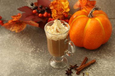 Sıcak bir içecek, üzerinde sonbahar yaprakları, balkabağı ve tarçın çubukları olan krem şantili temiz bir bardakta servis edilir. Samimi kurgu, sonbahar kutlamalarının özünü yakalıyor..