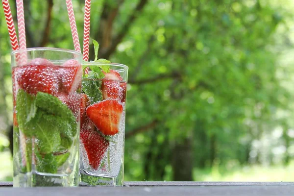 Літні холодні напої Полуничний коктейль зі свіжими ягодами та м'ятою у склянці на дерев'яному столі в саду, літній час . — стокове фото