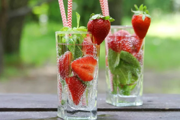 Bevande fredde estive Cocktail di fragole con bacche fresche e menta in vetro su tavolo di legno in giardino, estate . — Foto Stock