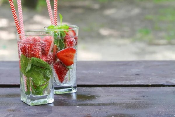 Yaz soğuk içecekler Bahçede ahşap masada cam taze çilek ve nane ile Çilek kokteyl, yaz.