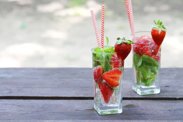 Bevande fredde estive Cocktail di fragole con bacche fresche e menta in vetro su tavolo di legno in giardino, estate . — Foto Stock