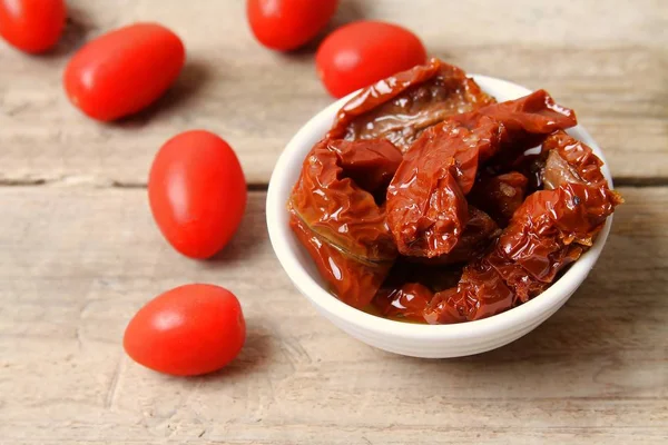 Ahşap arka planda masa üstünde güneş kurutulmuş domates üst görünümü.