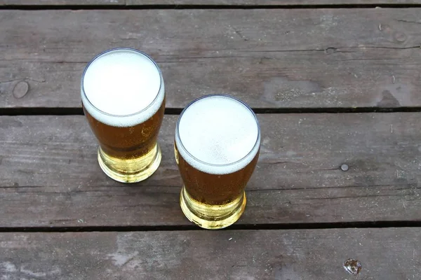 Ahşap masanın camında bira. Açık. Düz döşeme, üst görünüm.