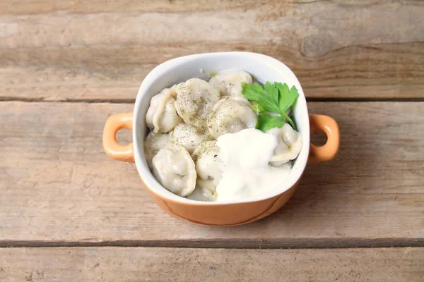 Geleneksel yemekler. Ravioli, ahşap masa üzerinde ekşi krema ile pelmeni. Düz yatıyordu.