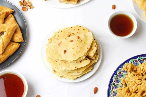 Geleneksel Tatar Yemekleri. Kystybyi (Patates püresiyle düz ekmek) Beyaz Masa 'nın ortasında. Düz Yat, Üst Görünüm.