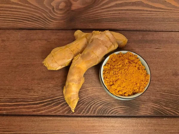 Çiğ organik zerdeçal kökü ve toz kürcuma longa, ahşap zemin üzerinde diyet besin. Düz yat, açık alan, kapat. Hint asıllı sağlıklı düşük kolesterol baharatları.