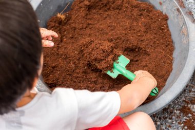 Küçük çocuk karışık toprak, arka bahçe ağaç dikmek için hazırlık için kürekle.
