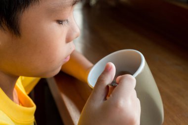 evde pencerenin yanında ahşap masada oturan küçük bir çocuk t