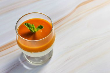Mermer bir masada bir bardak nane yaprakları ile mango püresi ile Panna cotta tatlı