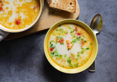 Sarı bir tabakta krema ve sebze ile Somon çorbası. bir havlu somon çorbası ile tencere. gemide ekmek. bir karanlık üzerinde