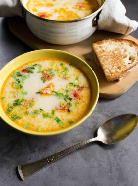 Sarı bir tabakta krema ve sebze ile Somon çorbası. bir havlu somon çorbası ile tencere. gemide ekmek. bir karanlık üzerinde