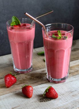 strawberry smoothie in a tall glass with metal straws. on a wooden table. with mint leaves.  clipart