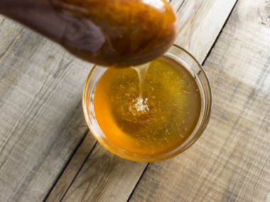 tahta kaşıkla tahta bir masa üzerinde cam bir kapta taze bal