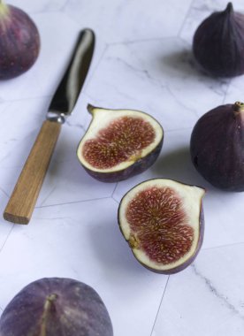 mermer bir masa üzerinde olgun incir. yarım meyve ve bıçak