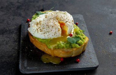 Avokado kremalı yumurta sarısı ve koyu arkaplanda ekmek tostu.
