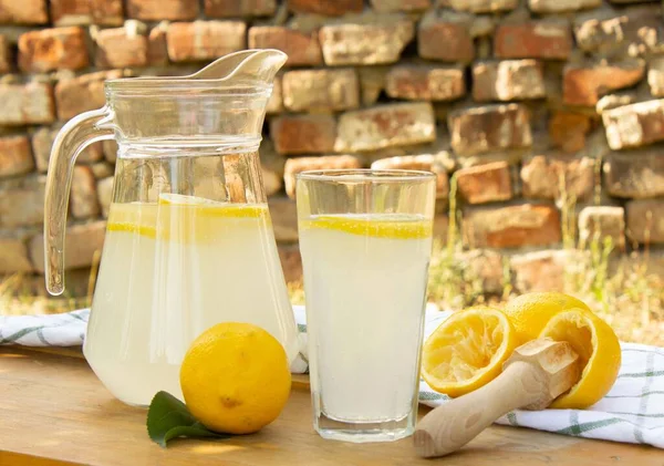Dışarıdaki Ahşap Bir Masada Cam Sürahi Limonata Olgun Sarı Limonlar — Stok fotoğraf