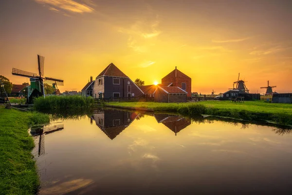 Günbatımı yukarıda çiftlik evleri ve Zaanse Schans'a Hollanda yel değirmenleri