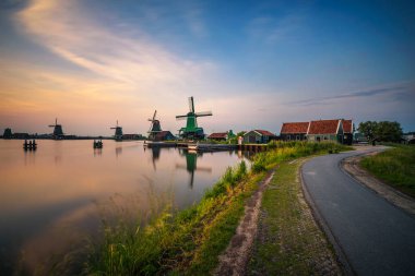 Günbatımı yukarıda çiftlik evleri ve Zaanse Schans'a Hollanda yel değirmenleri